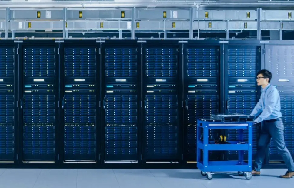 Blue-lit data center with server racks and cooling infrastructure.