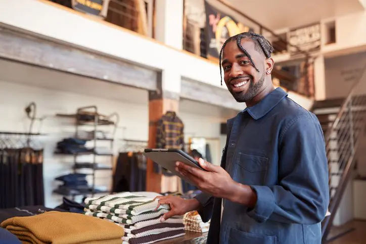 Male fashion store owner checking stock on tablet