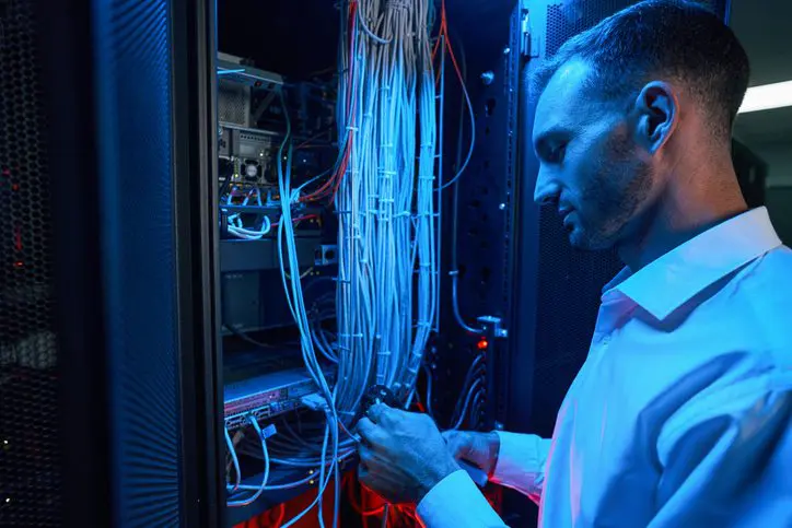 IT specialist configuring server cables in a data center.