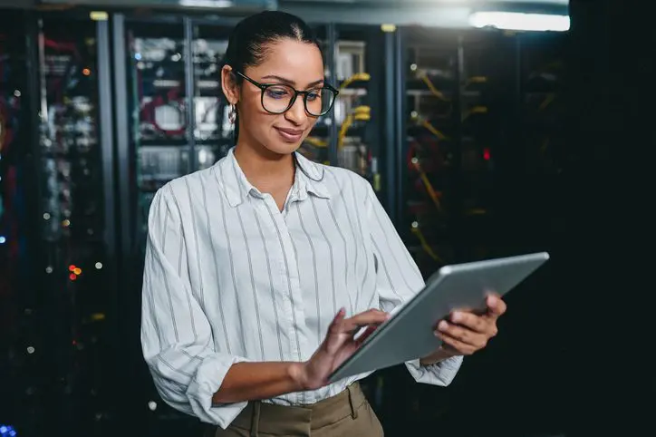 IT professional using a digital tablet in a server room.