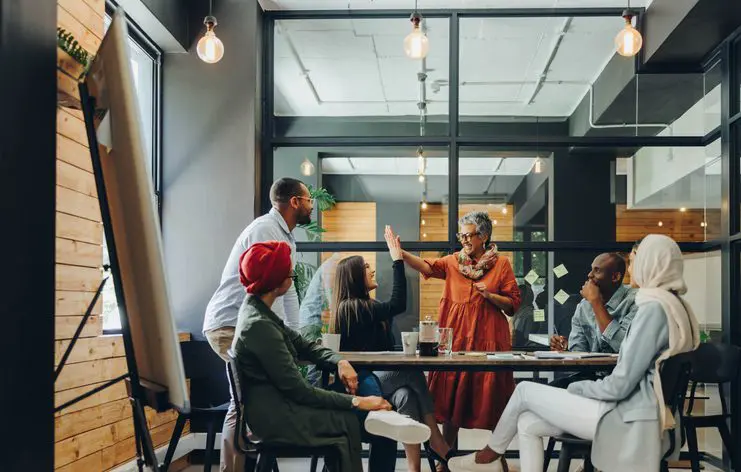 Team meeting with a speaker addressing colleagues in a glass-walled office room