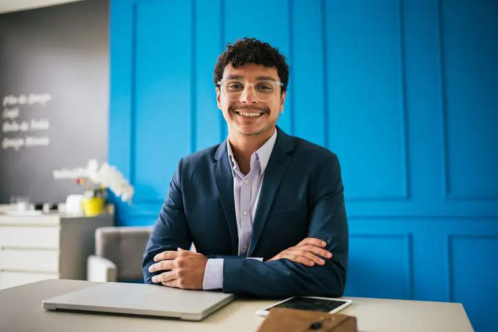 Confident young man smiling at his desk in a modern office.