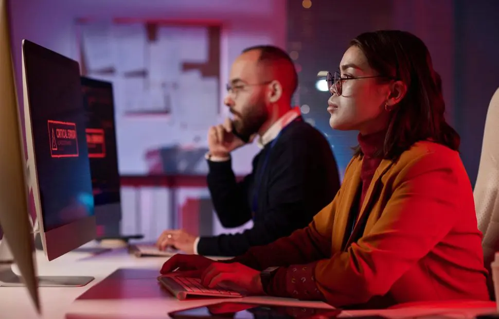 Team of professionals in discussion while seated in dark room.