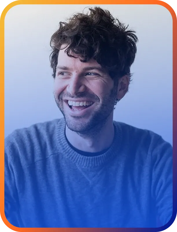 Man smiling warmly in front of a soft blue gradient backdrop.